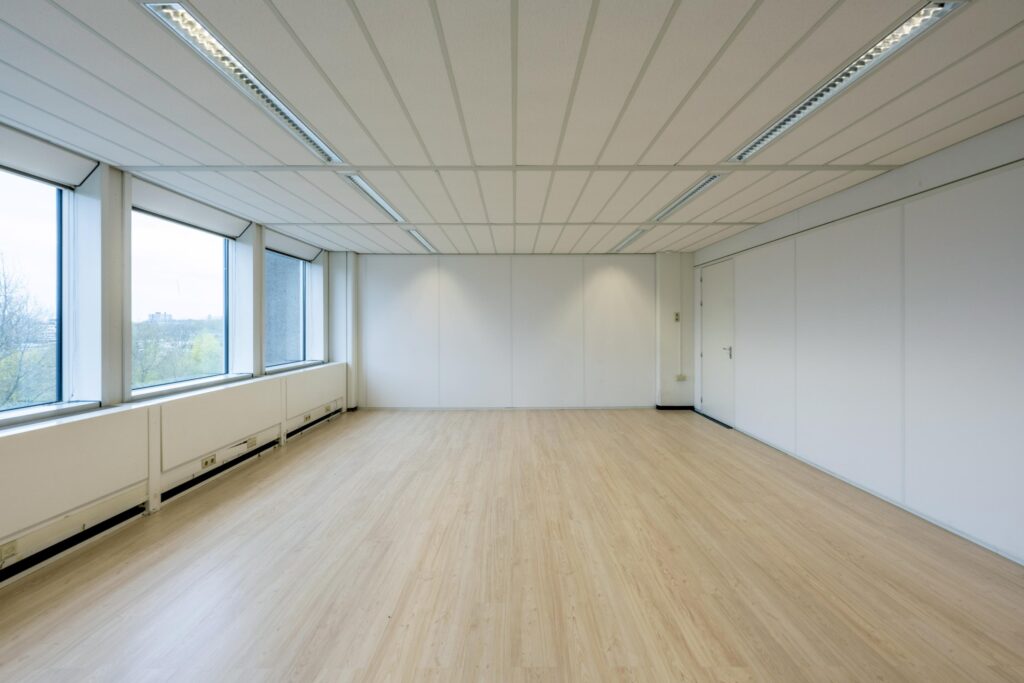 Empty office space with large windows and light wooden flooring at Laan van Kronenburg.